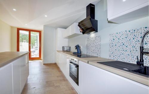 une cuisine avec des armoires blanches, un évier et une cuisinière dans l'établissement Cozy Home In Saint-Génis-Des-Fontaines, à Saint-Génis