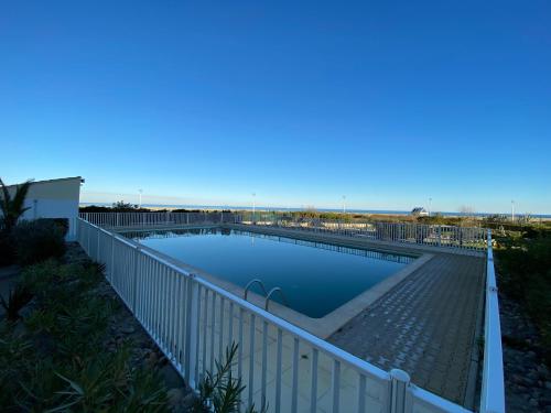 une piscine entourée d'une clôture blanche. dans l'établissement Appartement T2 vue mer port-leucate accès direct plage avec piscine et ascenseur port leucate, à Leucate