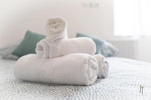 - une pile de serviettes assises sur un lit dans l'établissement Charmant studio proche de toutes commodités, à Saint-Quentin