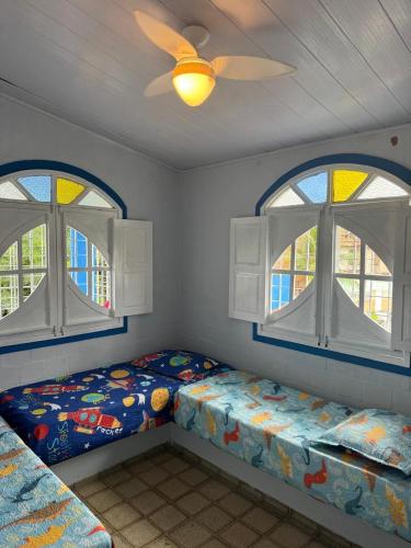 ein Schlafzimmer mit zwei Betten und zwei Fenstern in der Unterkunft Carneiros House in Praia dos Carneiros