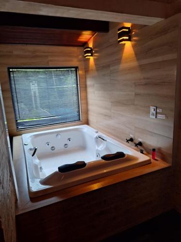 a large bath tub in a bathroom with a window at Chalé das Orquídeas in Monte Verde