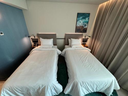 two beds in a room with white sheets at Novotel Recife Marina in Recife