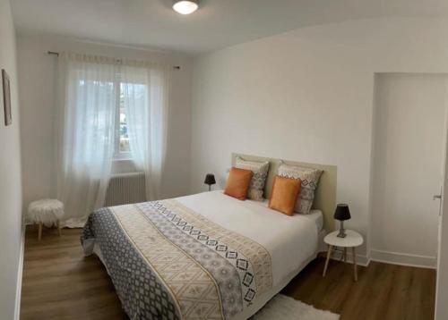 - une chambre blanche avec un grand lit et des oreillers orange dans l'établissement Au Sunrise T4, à Angoulême