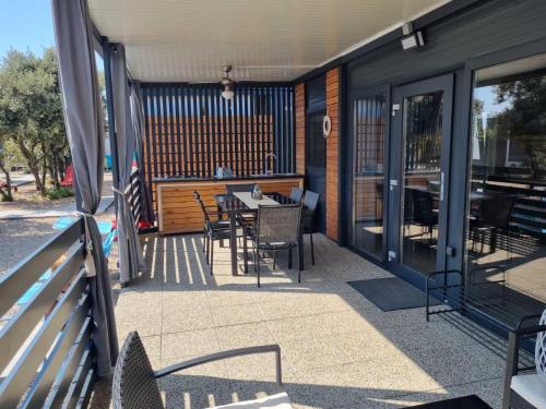 een patio met een tafel en stoelen op een huis bij Mobile Home Elica, Pirovac in Pirovac