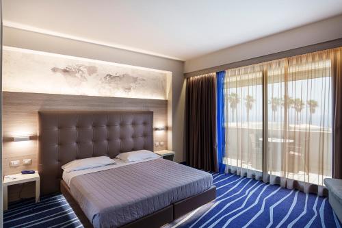 a hotel room with a bed and a large window at President Park Hotel in Acitrezza