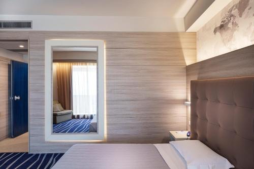 a bedroom with a mirror and a bed and a bathroom at President Park Hotel in Acitrezza