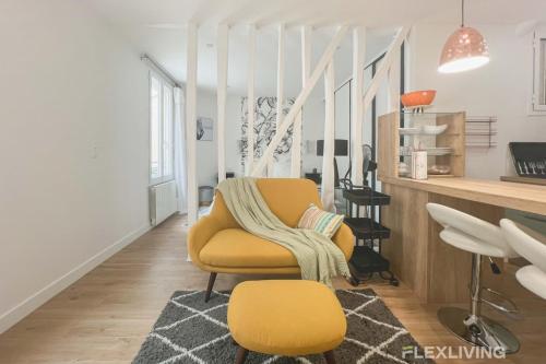 un salon avec une chaise jaune et une table dans l'établissement Flexliving - T2 - Garibaldi, à Paris