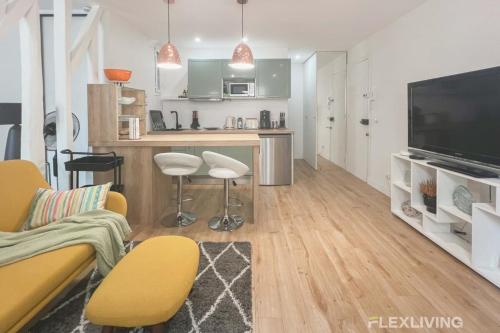 Il comprend un salon doté d'un canapé et une cuisine équipée d'une télévision. dans l'établissement Flexliving - T2 - Garibaldi, à Paris