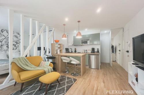 un salon avec une chaise jaune et une cuisine dans l'établissement Flexliving - T2 - Garibaldi, à Paris