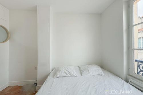 un lit blanc dans une chambre avec une fenêtre dans l'établissement Flexliving - room - Augereau, à Paris