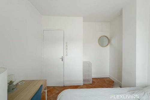 Cette chambre blanche dispose d'une porte, d'une table et d'un lit. dans l'établissement Flexliving - room - Augereau, à Paris