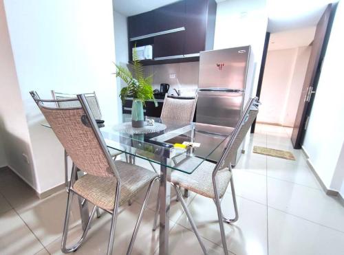 a glass table with chairs and a refrigerator in a kitchen at Departamento en Condominio Barak in Santa Cruz de la Sierra