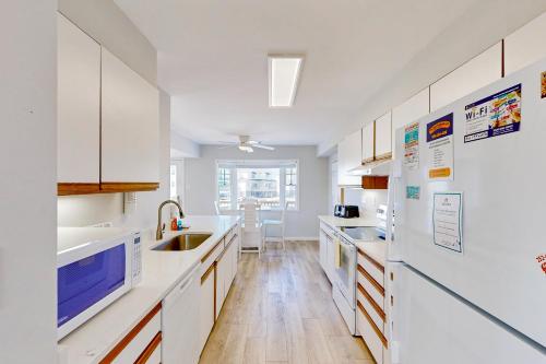 a white kitchen with white appliances and wooden floors at Snapper #18B-CAC in Buxton