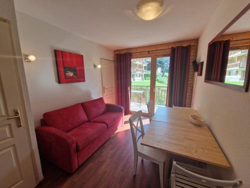 un salon avec un canapé rouge et une table en bois dans l'établissement Appart 2 pièces, 4 pers, proche télécabine et commerces, balcon au sud, casier à skis - FR-1-265-206, à Valfréjus