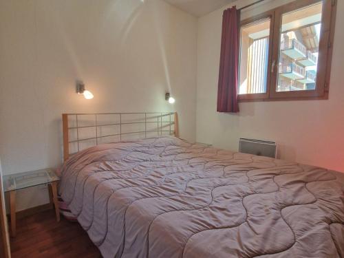 une chambre avec un grand lit avec une fenêtre dans l'établissement Appart 2 pièces, 4 pers, proche télécabine et commerces, balcon au sud, casier à skis - FR-1-265-206, à Valfréjus