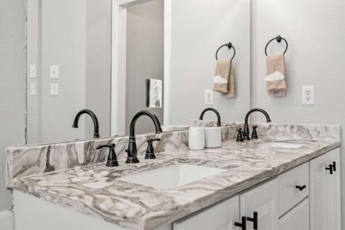 La salle de bains est pourvue de 2 lavabos et d'un comptoir en marbre. dans l'établissement Extended Stay Fun Outdoor Games, Gym, BBQ, Dining, à Lewisville