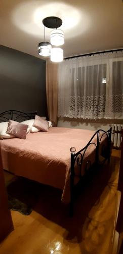 a bed in a bedroom with a window and a light at Apartament Grodzka in Wałbrzych