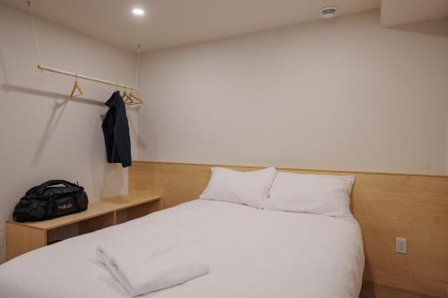 a bedroom with a bed with white sheets and a bag at Chalet 5 OST Shefford in Shefford