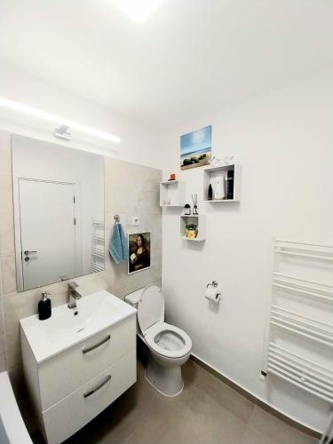 a white bathroom with a toilet and a sink at Panoramic City View Apartment in Târgu-Mureş