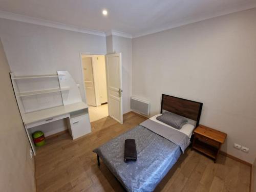 une petite chambre avec un lit et un bureau dans l'établissement Le Lotus - appartement, à Béziers