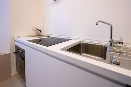 a kitchen with a stainless steel sink and white counters at Appartamento Garibaldi in Morbegno