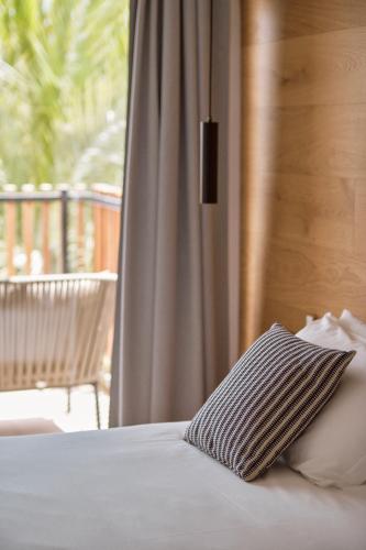 a bed with a pillow and a window at Las Gaviotas Suites Hotel & Spa in Playa de Muro