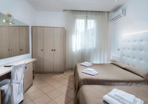 a bedroom with two beds and a sink and a mirror at Hotel Mediterraneo in Pesaro
