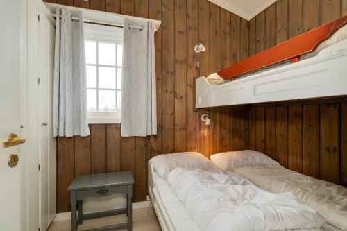 a bed in a room with wooden walls and a window at Bitigrenda G in Beitostøl