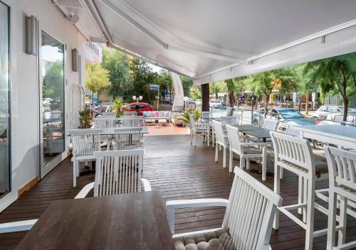 a patio with white chairs and tables and a pool at Hotel Mediterraneo in Pesaro