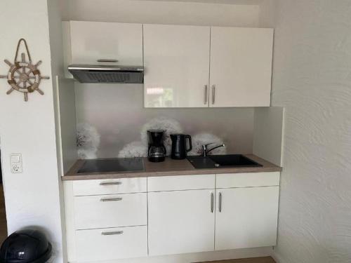 a kitchen with white cabinets and a sink at Ferienwohnung Tee Tied in Dornumersiel