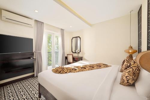 a white bedroom with a bed and a television at Hoi An Canal House Riverside By Haviland in Hoi An