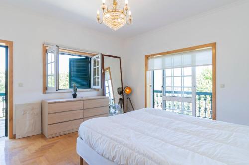 a bedroom with a large white bed and windows at Quinta do Fontanário by LovelyStay in Celorico de Basto