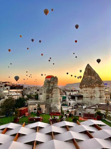 a group of hot air balloons flying over a city with buildings at Century Cave Hotel in Goreme