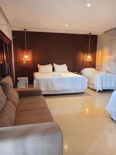 a hotel room with two beds and a couch at Pousada Gostoso Paradise in São Miguel do Gostoso