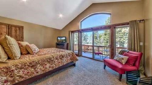a bedroom with a bed and a chair and a window at Lv12 luxury villa with hot tub, close to skiing in Glenbrook