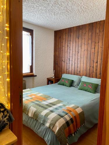 a bedroom with a bed with a wooden wall at La casa nel verde, un nido accogliente con vista in Folgarida