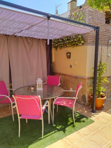 a patio with a table and chairs under a purple canopy at Acogedor apartamento loft in Alhaurín de la Torre