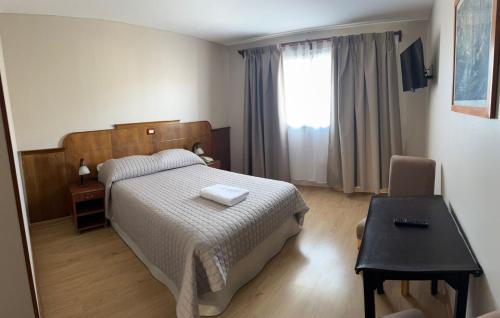 a bedroom with a bed and a table and a window at Hotel Picos Del Sur in El Calafate