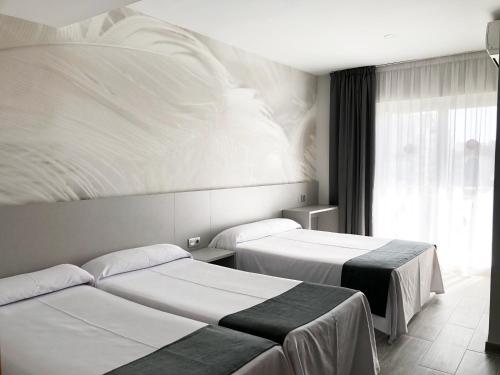 a hotel room with two beds and a window at Hotel Maria del Mar in Lloret de Mar