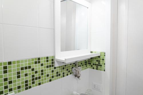 a bathroom with a mirror and a green tiled wall at B&B VistaMare in Civitavecchia