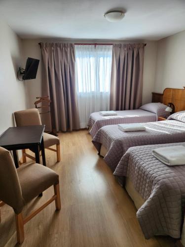 a room with three beds and a table and chairs at Hotel Picos Del Sur in El Calafate