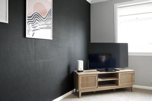 a living room with a tv on a wooden cabinet at Barclay House in Livingston