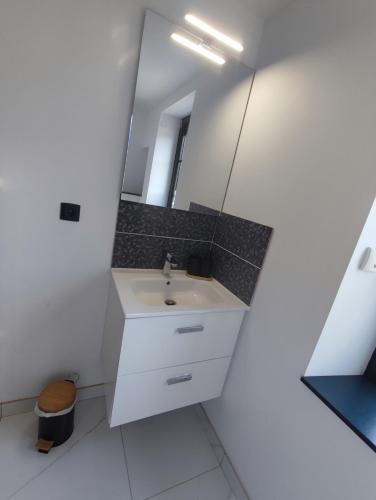 une salle de bain blanche avec un lavabo et un miroir dans l'établissement La petite maison de Laura située entre Caen Bayeux la mer, à Bretteville-lʼOrgueilleuse