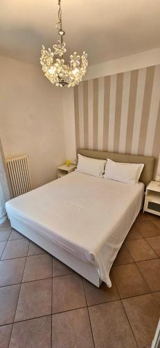 a bedroom with a large white bed with a chandelier at APPARTAMENTO A DUE PASSI DAL MARE By VILLA FIORITA in Cattolica