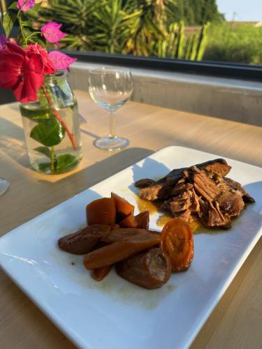 a plate of food on a table with a wine glass at Hôtel La Petite Bohème in Le Lavandou
