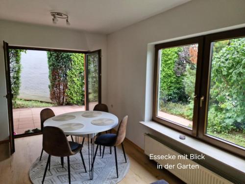 a dining room with a table and chairs and windows at Ferienwohnung Edgar und 300 qm Garten Trier Mosel Eifel in Mertesdorf