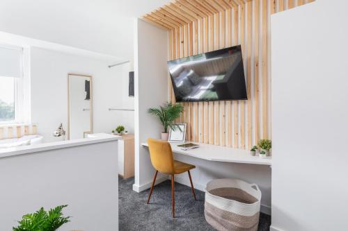 a bathroom with a desk and a television on a wall at Stylish Studio Apt in Leeds in Headingley