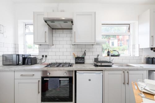 a kitchen with white cabinets and a stove top oven at Stylish Studio Apt in Leeds in Headingley