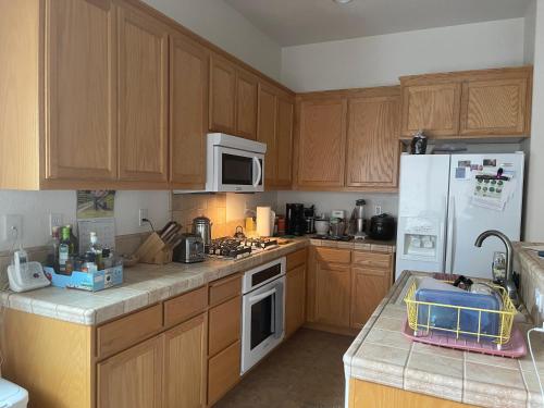 a kitchen with wooden cabinets and a white refrigerator at Comfort and Style Queen bedroom in Vacaville