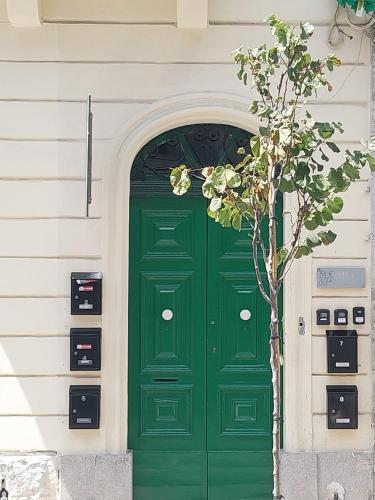 a green door on a white building with a tree at Studio flat 7A in Hamrun